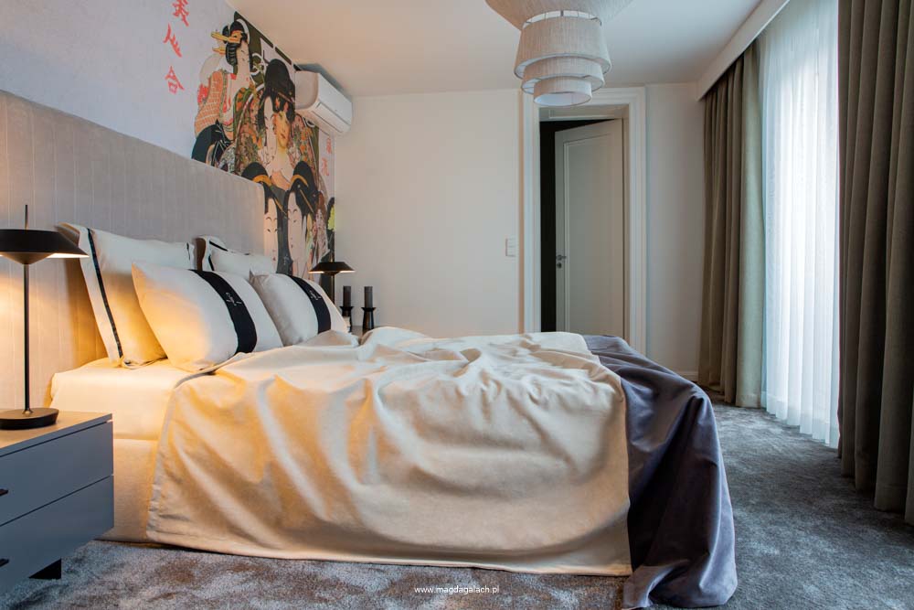 luksusowa sypialnia z beżowym aksamitnym łóżkiem, tapetą oraz z poduszkami z monogramem
