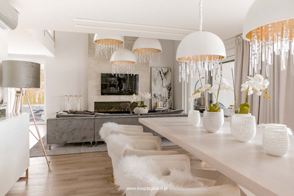 luksusowy salon z jadalnią z kryształowymi lampami z białym stołem i szarym narożnikiem projekt Magda Gałach